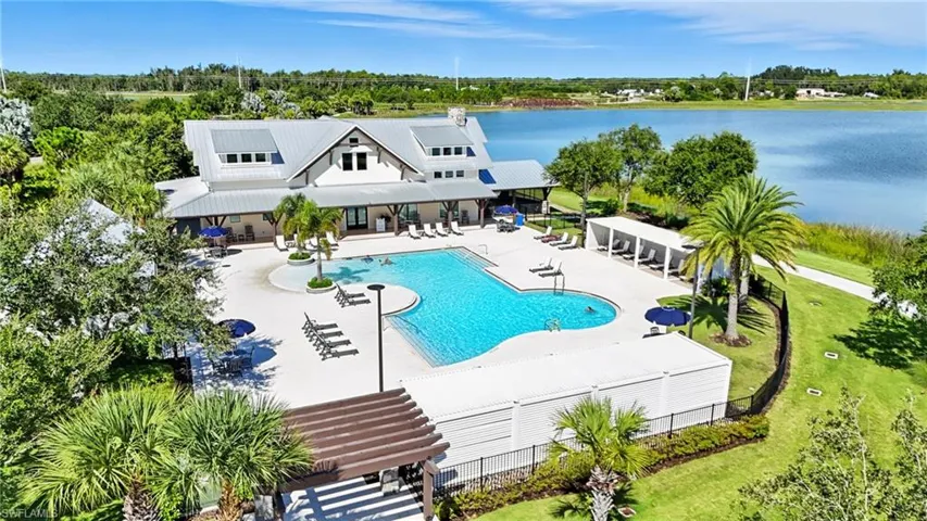 Community pool featuring a patio, a water view, and view of scattered trees