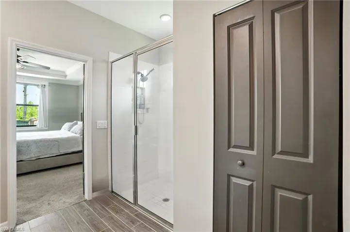 Ensuite bathroom with a shower stall, wood tiled floors, and a closet