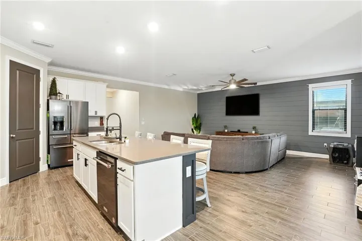 Kitchen with white cabinetry, a kitchen breakfast bar, crown molding, open floor plan, and stainless steel appliances