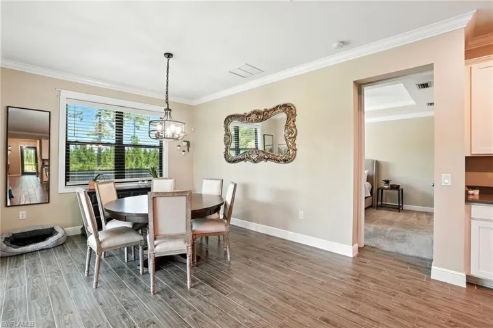 Dining space with ornamental molding, light wood-style floors, and a chandelier