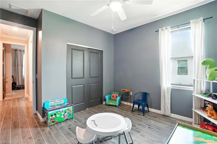Playroom with wood tiled floors, ceiling fan, and ornamental molding