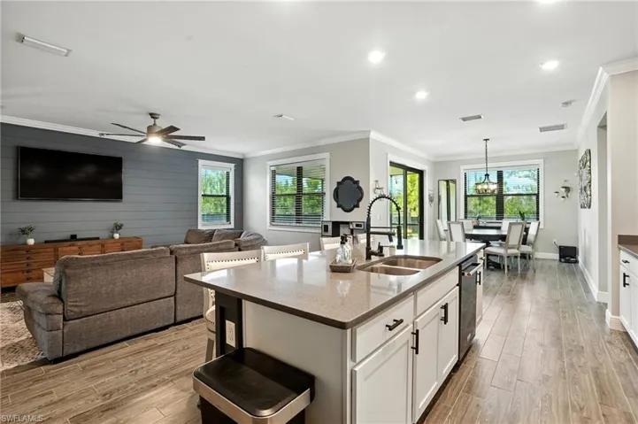 Kitchen featuring a kitchen bar, white cabinetry, light wood-style floors, light stone counters, and open floor plan
