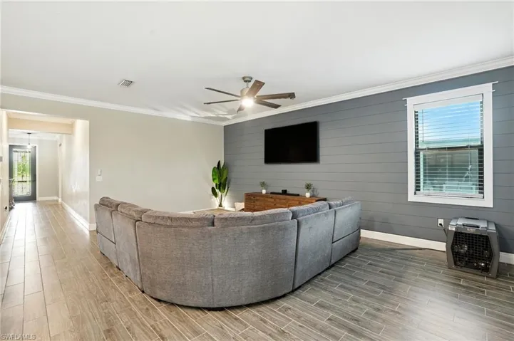 Living room featuring crown molding, wood tiled floors, ceiling fan, heating unit, and wood walls