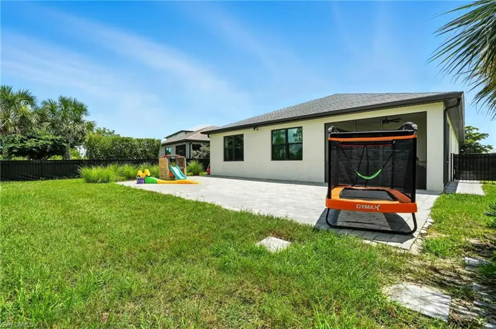 Rear view of house with a playground, stucco siding, a patio, and roof with shingles