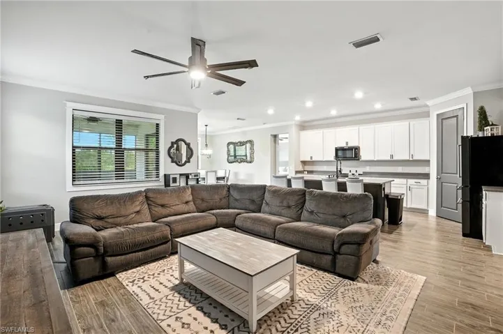 Living room with ornamental molding, light wood-style flooring, recessed lighting, and a ceiling fan