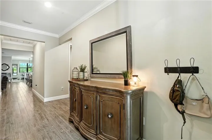 Corridor with ornamental molding and light wood-style floors