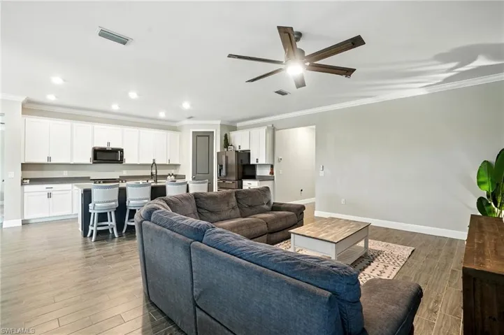 Living area featuring ornamental molding, light wood-style floors, ceiling fan, and recessed lighting