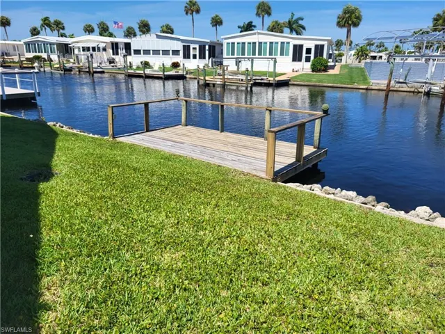 View of dock with a water view and a lawn