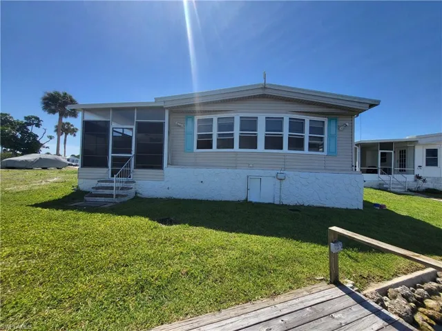 Back of house featuring a sunroom and a lawn