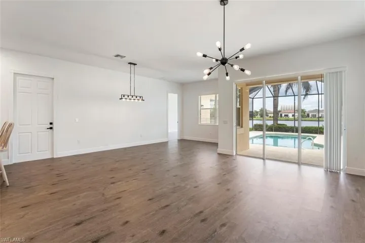 Unfurnished living room with a chandelier and dark wood-type flooring
