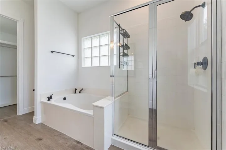 Bathroom featuring a shower stall, a garden tub, and wood finished floors