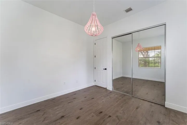 Unfurnished bedroom with wood finished floors, a chandelier, and a closet