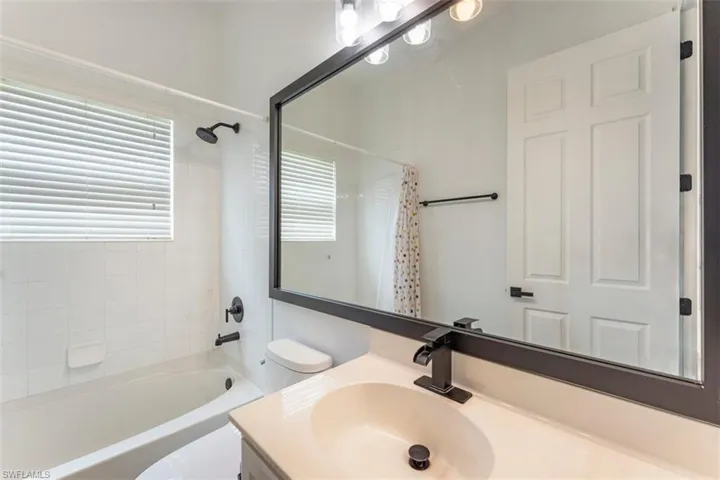 Bathroom featuring vanity, healthy amount of natural light, and shower / bath combination with curtain