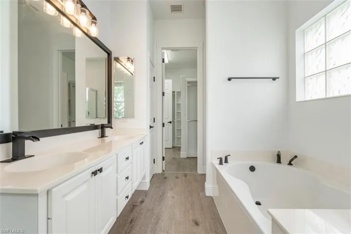 Bathroom with double vanity, wood finished floors, and a garden tub
