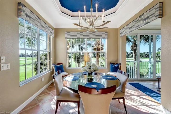 Dining room featuring a tray ceiling, ornamental molding, baseboards, a chandelier