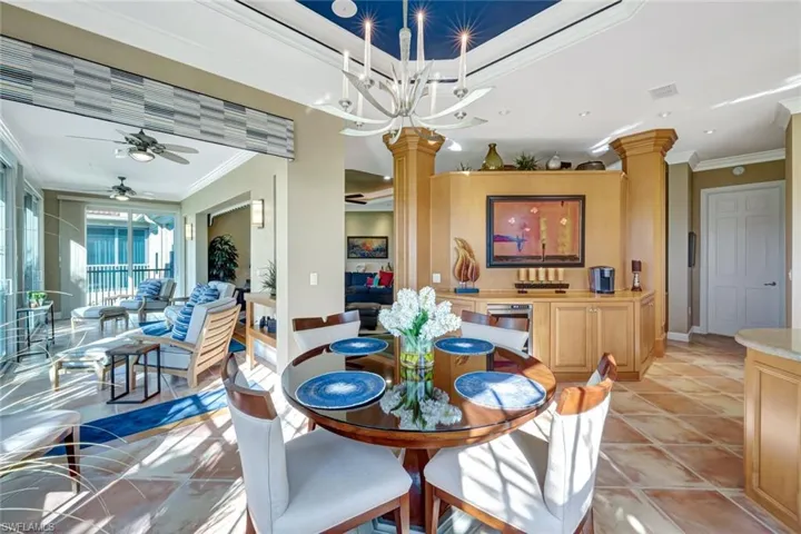 Dining room with decorative columns, light tile patterned floors, crown molding, and a ceiling fan