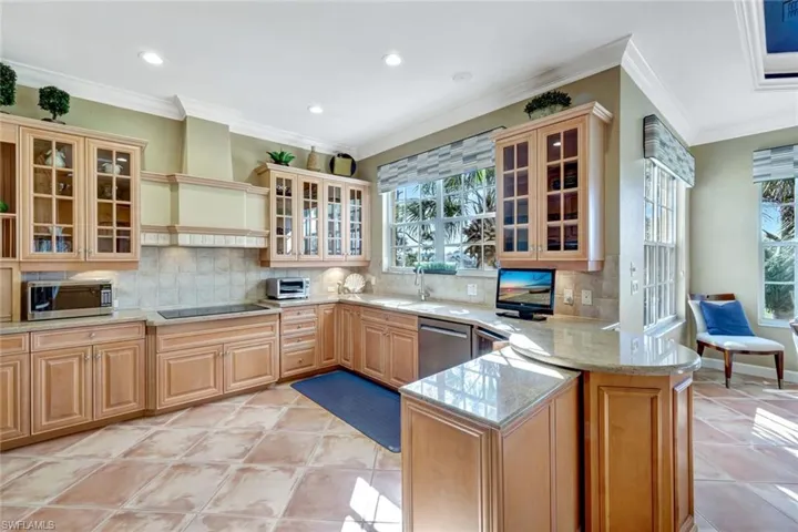 Kitchen with a sink, a peninsula, stainless steel appliances, light  and custom range hood