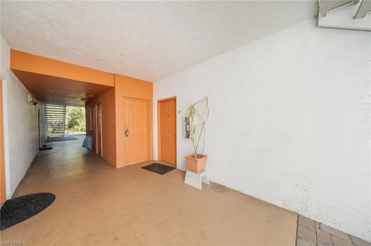Hall with a textured wall, concrete floors, and a textured ceiling