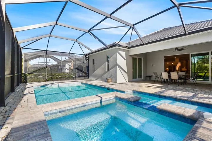 View of pool with glass enclosure, ceiling fan, and a patio