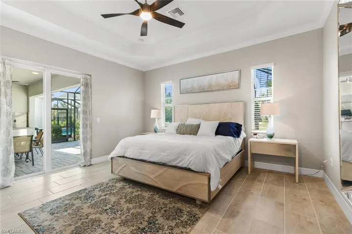 Bedroom with ceiling fan, access to exterior, crown molding, and a tray ceiling
