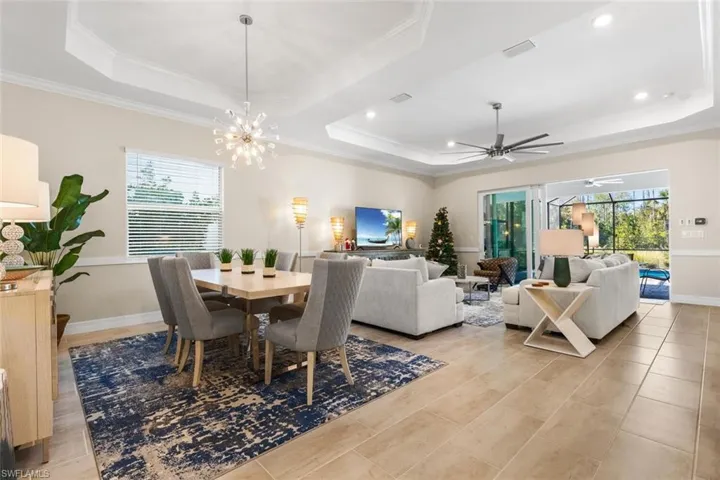 Dining room featuring a healthy amount of sunlight, ceiling fan with notable chandelier, a raised ceiling, and crown molding