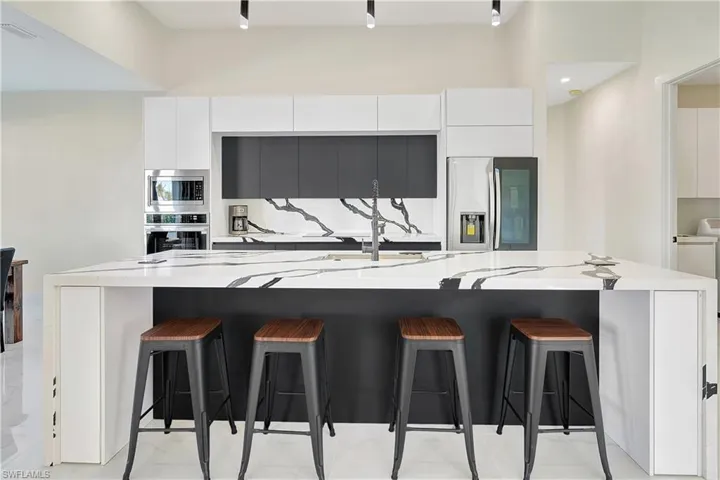 Kitchen featuring modern cabinets, a breakfast bar, stainless steel appliances, and a large island with sink