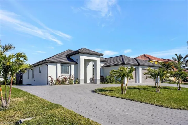 View of front facade with a front yard, stucco siding, decorative driveway, and a garage