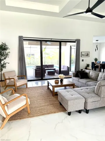 Living area featuring ceiling fan, plenty of natural light, marble finish flooring, and beam ceiling