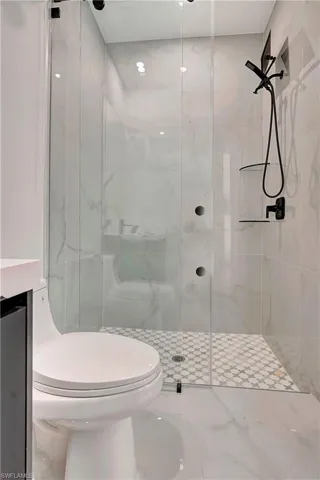 Full bath with a marble finish shower, vanity, and tile patterned floors