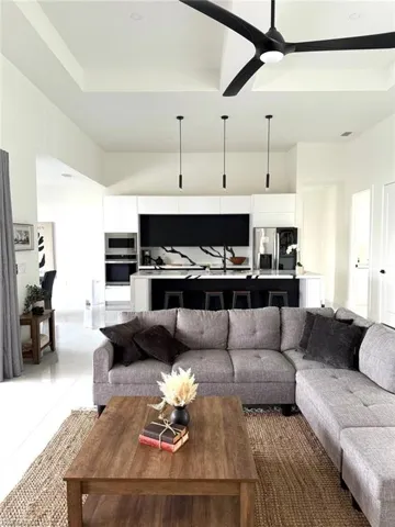 Living room with tile patterned floors, a tray ceiling, and ceiling fan