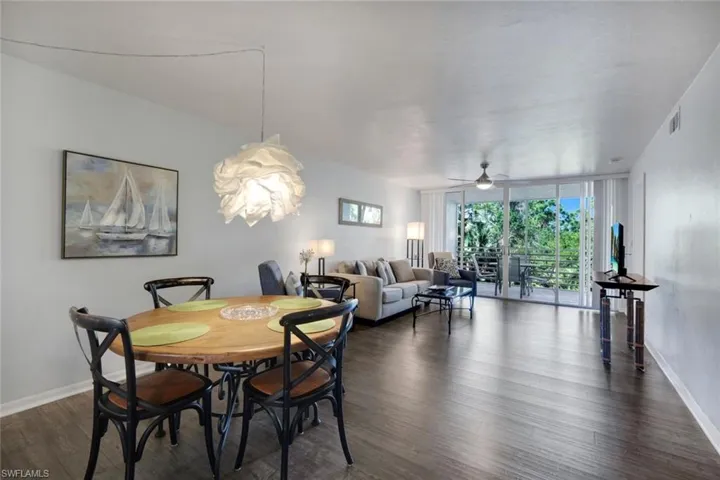 Open-concept living and dining area featuring dark wood-finish flooring, a contemporary pendant light fixture, and a ceiling fan