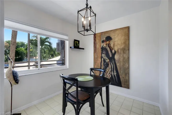 Bright interior space featuring a large window with roller shades, white walls, and light-colored tile flooring