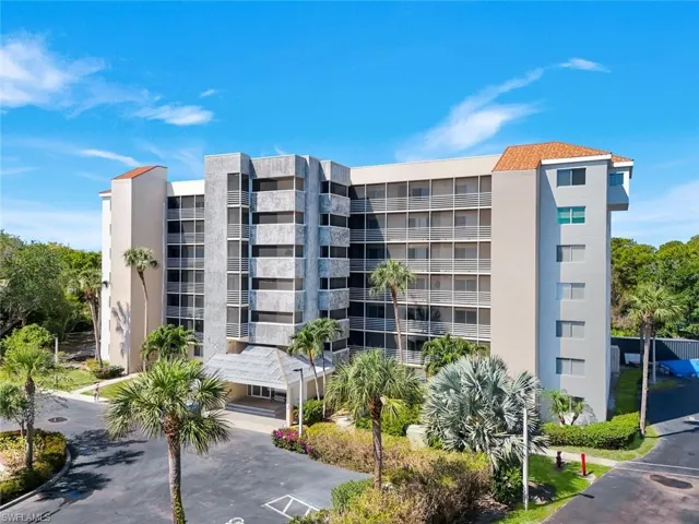 Multi-story building featuring a neutral-toned exterior, multiple private balconies, and a tiled roof accent
