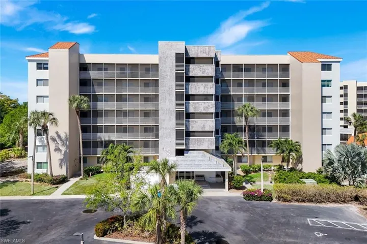 Multi-story residential building with screened balconies, a tiled roof accent, and a covered entrance