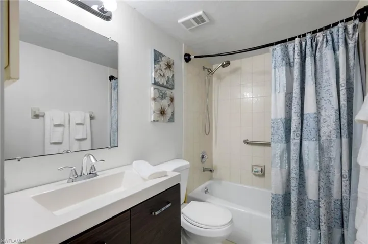 Bathroom featuring a modern vanity with an integrated sink, chrome faucet, and dark wood-finish cabinetry