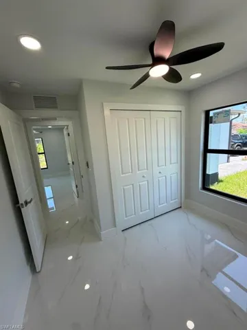 Room featuring white tile flooring with subtle veining, a modern ceiling fan with integrated lighting, recessed lighting, and a window with black trim