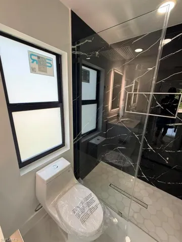 Modern bathroom featuring a frameless glass shower enclosure with hex tile flooring and a linear drain