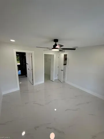 Spacious room featuring large format tile flooring with subtle veining, a ceiling fan with integrated lighting, recessed ceiling lighting, and crisp white walls and trim