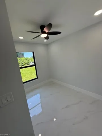 Interior room featuring a contemporary ceiling fan with integrated lighting, recessed lighting fixtures, a window with dark framing, light-colored walls, and large format polished tile flooring