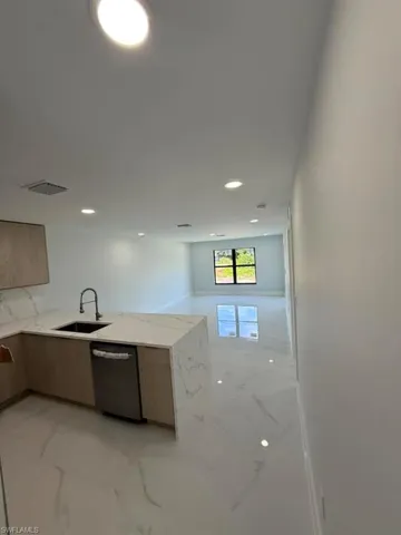 Open-concept kitchen and living area featuring a large island with an undermount sink and gooseneck faucet