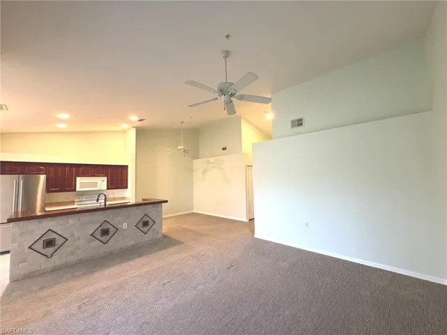 Unfurnished living room featuring vaulted ceiling, light carpet, ceiling fan, and recessed lighting
