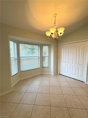 Unfurnished dining area with a chandelier and light tile patterned floors