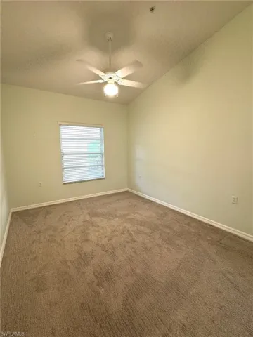 Unfurnished room featuring dark carpet, a textured ceiling, and a ceiling fan