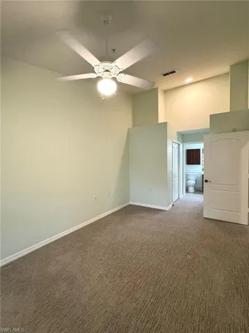 Unfurnished room featuring a high ceiling, carpet, and ceiling fan