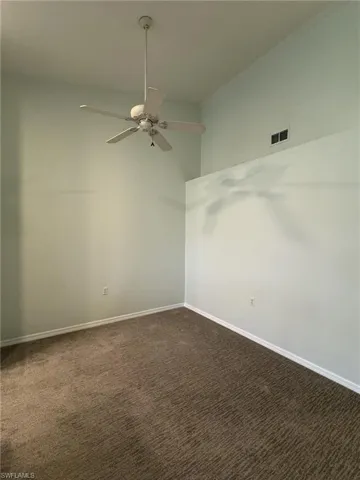 Spare room with dark colored carpet and a ceiling fan