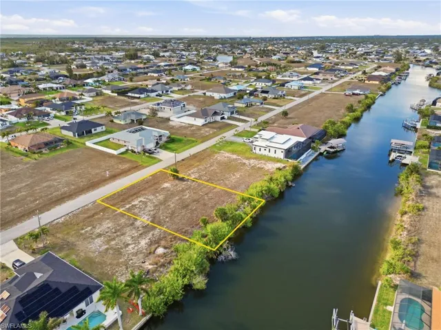 Aerial view of residential area featuring property boundaries highlighted and a nearby body of water