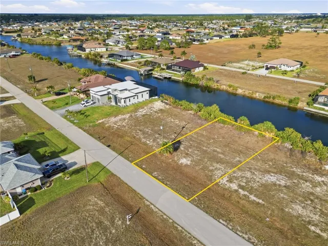 Aerial perspective of suburban area featuring a large body of water and property boundaries highlighted