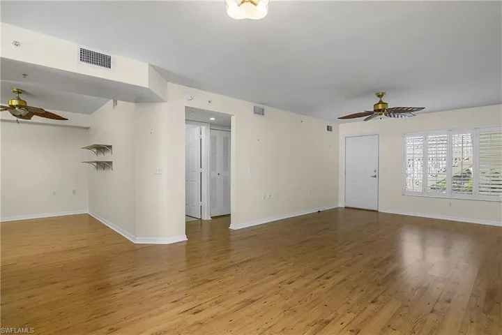Unfurnished living room featuring wood finished floors, ceiling fan, and visible vents