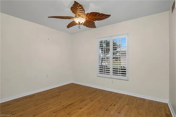 Unfurnished room with visible vents, baseboards, a ceiling fan, and wood finished floors