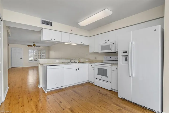 Kitchen featuring visible vents, a sink, light countertops, white appliances, and light wood-style flooring